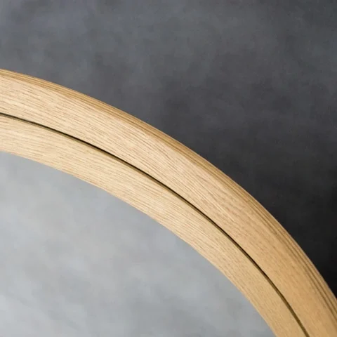 Detail eines runden Spiegelrahmens aus Holz mit sichtbarer Maserung und Spiegelkante